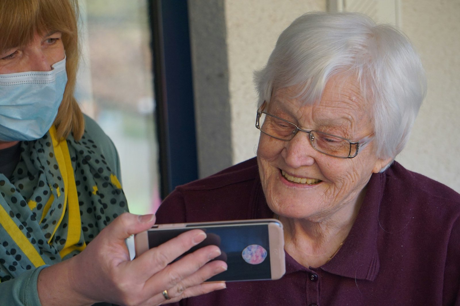 a senior smiling at something they are being shown on a phone