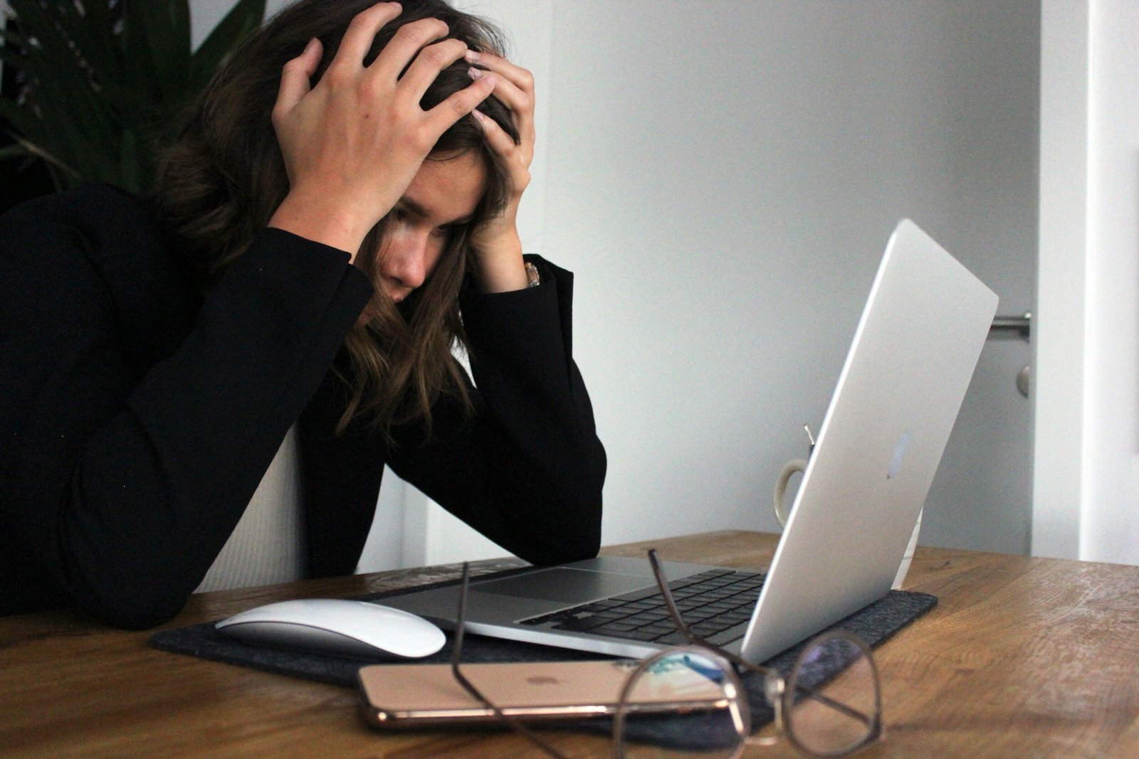 woman in front of laptop holding her head in her hands