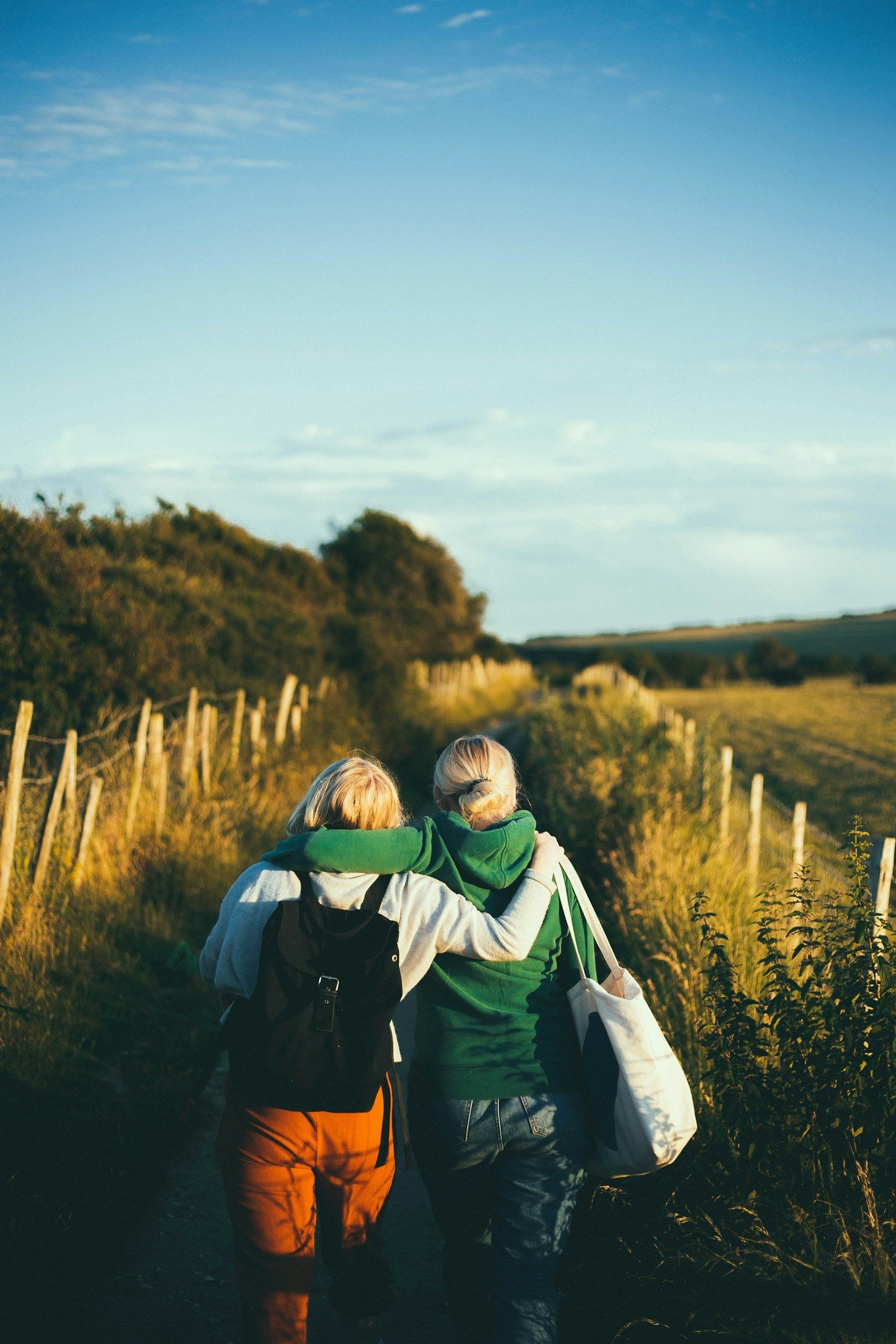 Two women walking along a path with arms linked