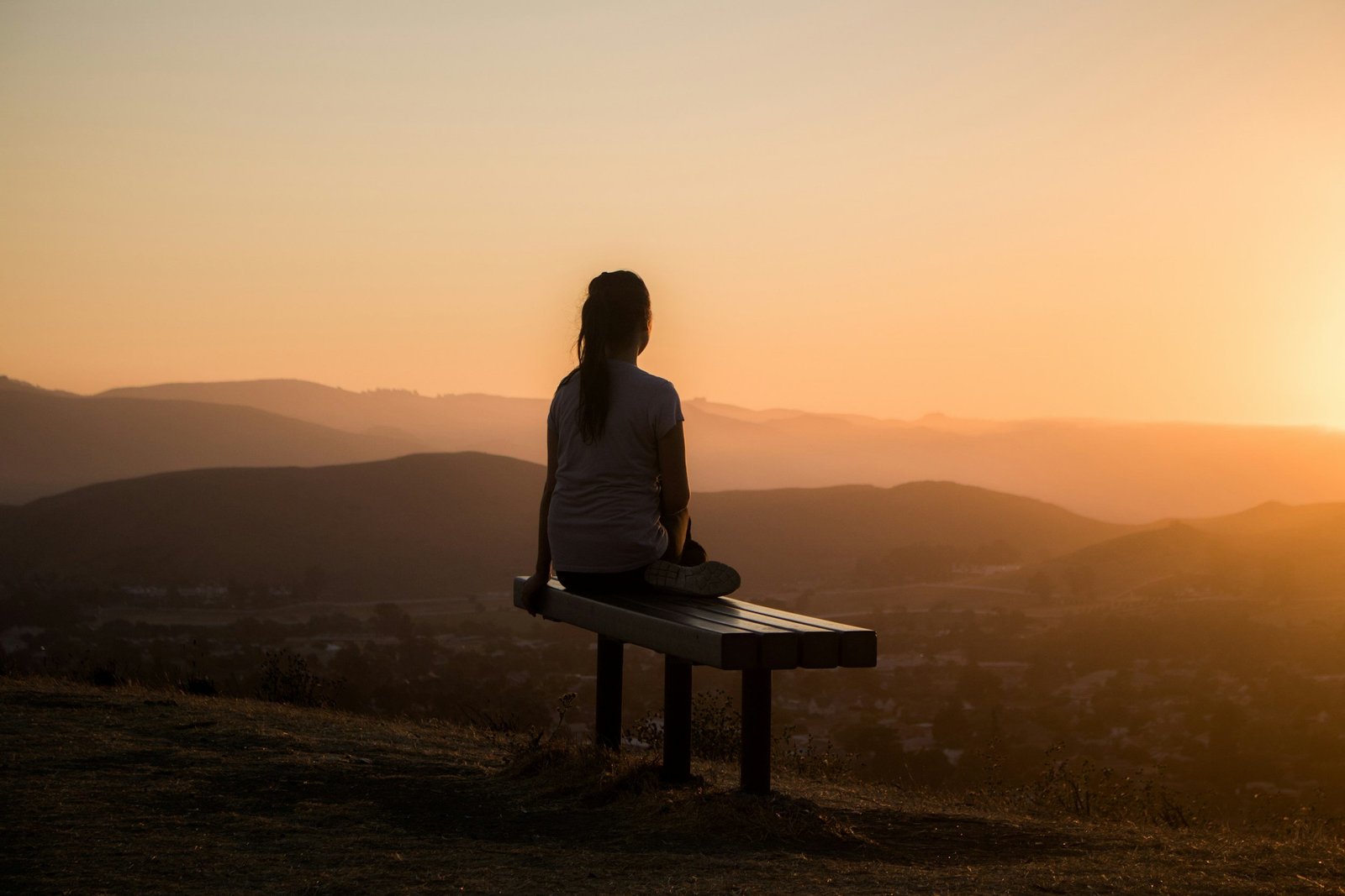 A woman sitting on a bench overlooking the desert