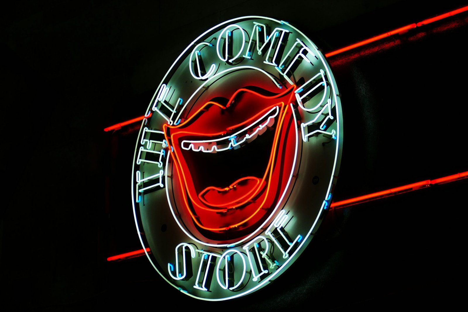 A round neon sign that says The Comedy Store with an open laughing mouth in the middle